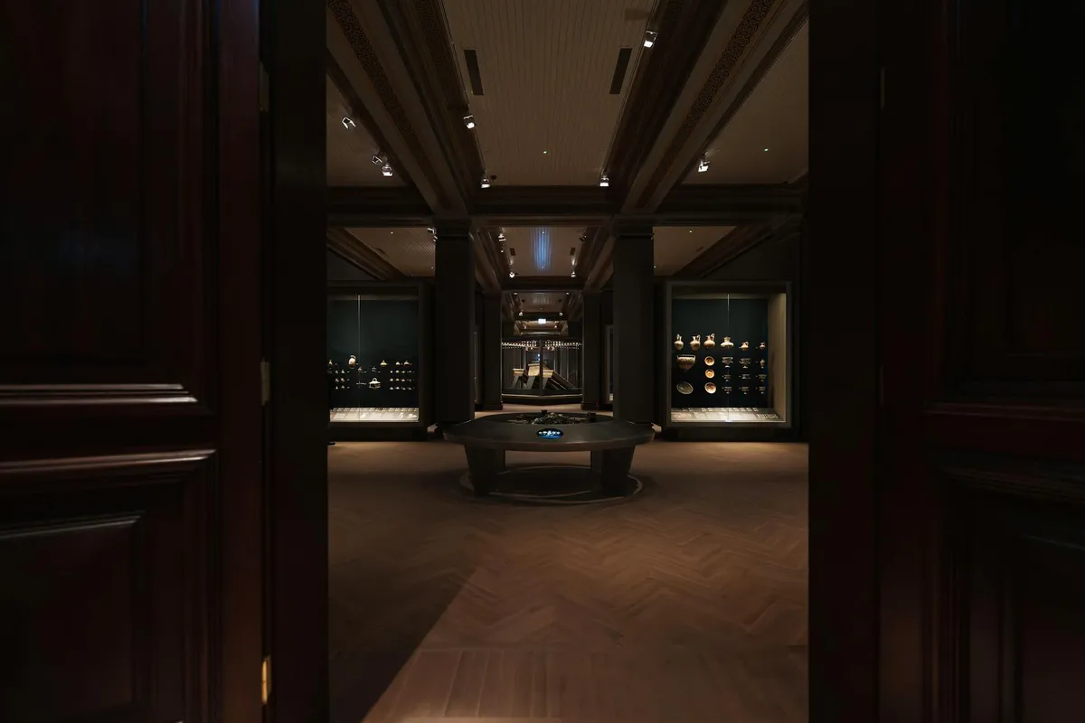 A quiet museum gallery interior with wooden vitrines and adobe walls